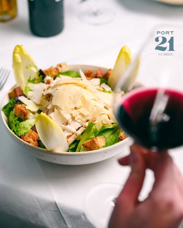 Salad with parmesan shavings and croutons, a glass of red wine