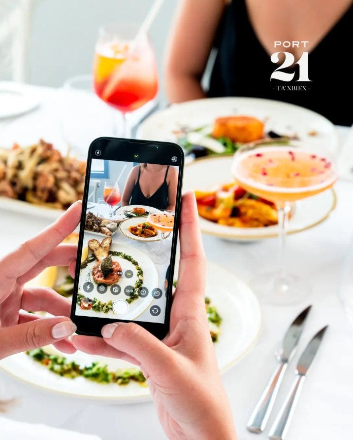 A guest photographing plates of food and cocktails at Port 21