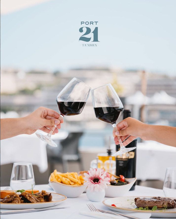 Two glasses of red wine raised over a table on the terrace