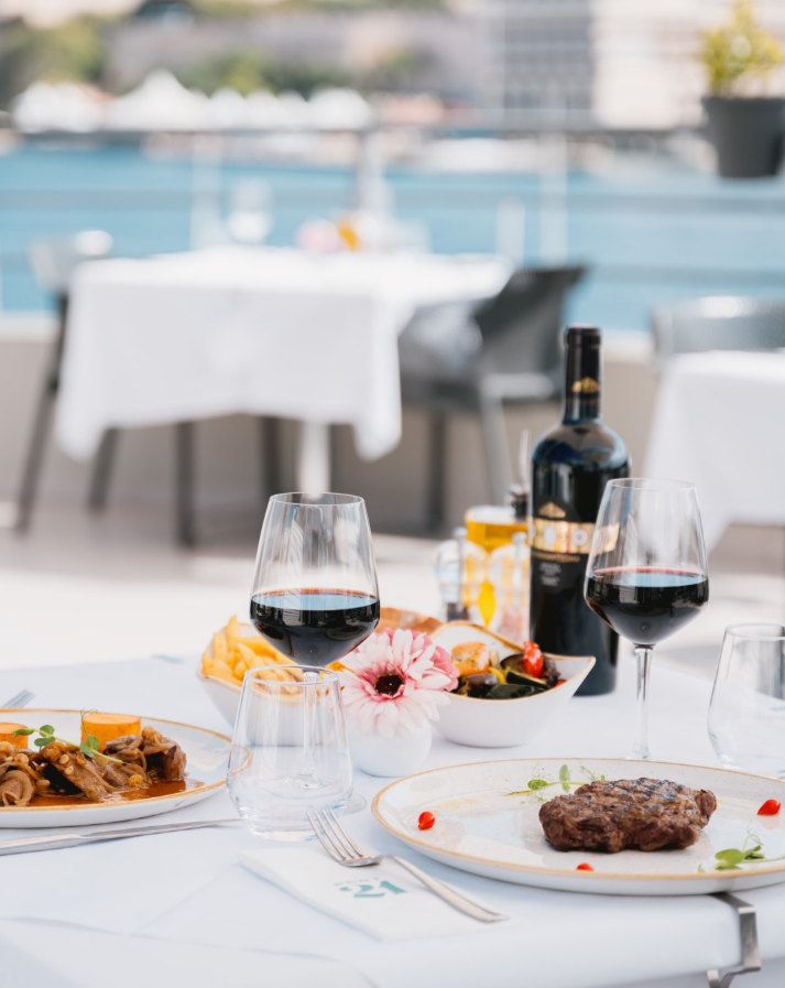 A table on the Port 21 terrace with red wine and plates, the harbour behind